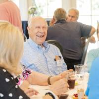 Ken Fridsma smiling at center of photo, sitting at table with other event attendees